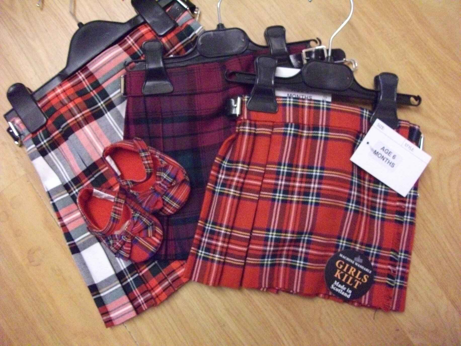 Three different sized and coloured tartan kilts with small tartan booties on top. Photo