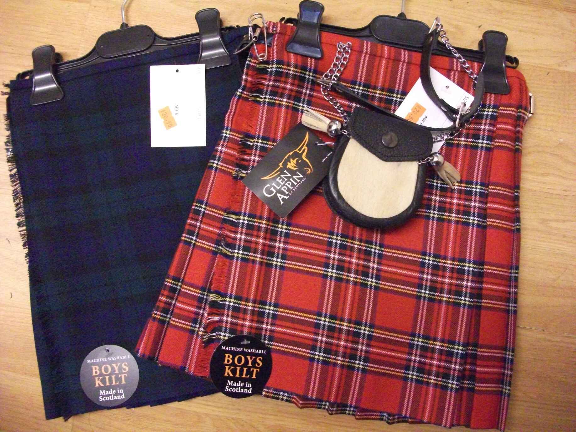 Two kilts; one blue and one red tartan. The red kilt has a black leather and white furr sporran. Photo