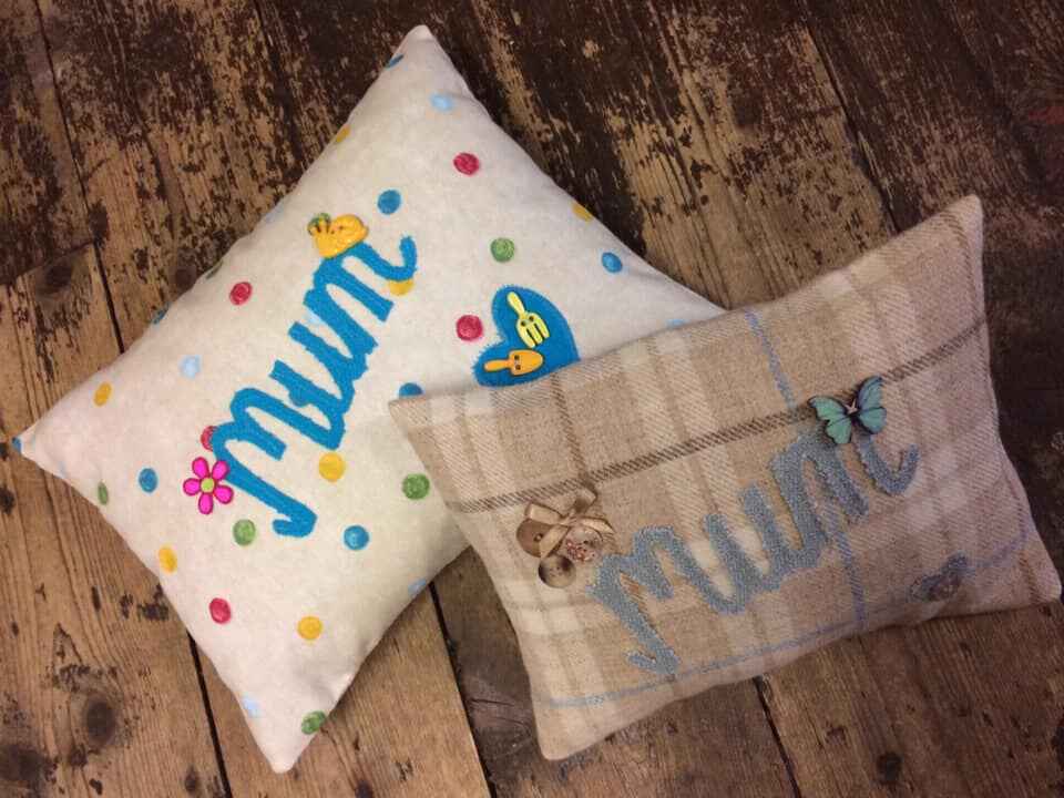 Two rectangle cushions in different fabric with ‘mum’ and some fabric decorations attached. Photo