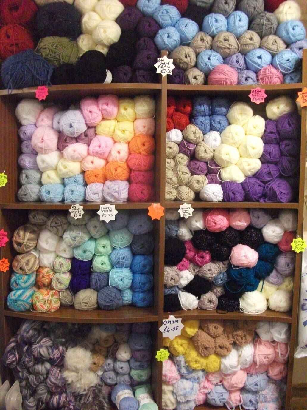 Shop shelving filled with balls of different colour wools. Photo